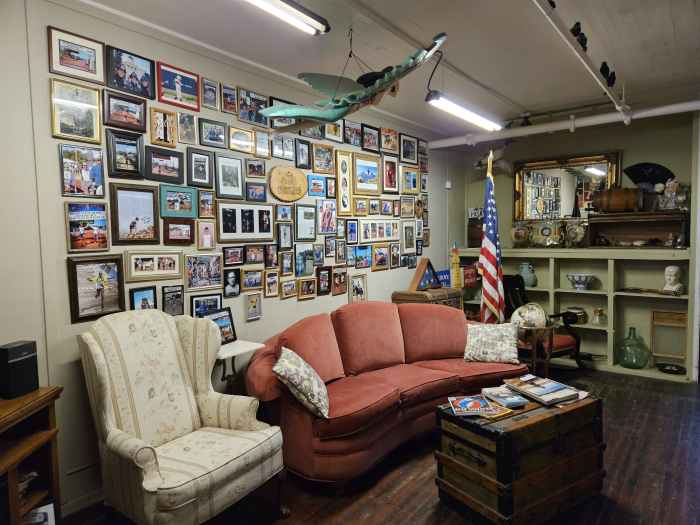 A massage studio waiting room with a light colored arm chair and a salmon couch in front of a gallery wall and an American flag